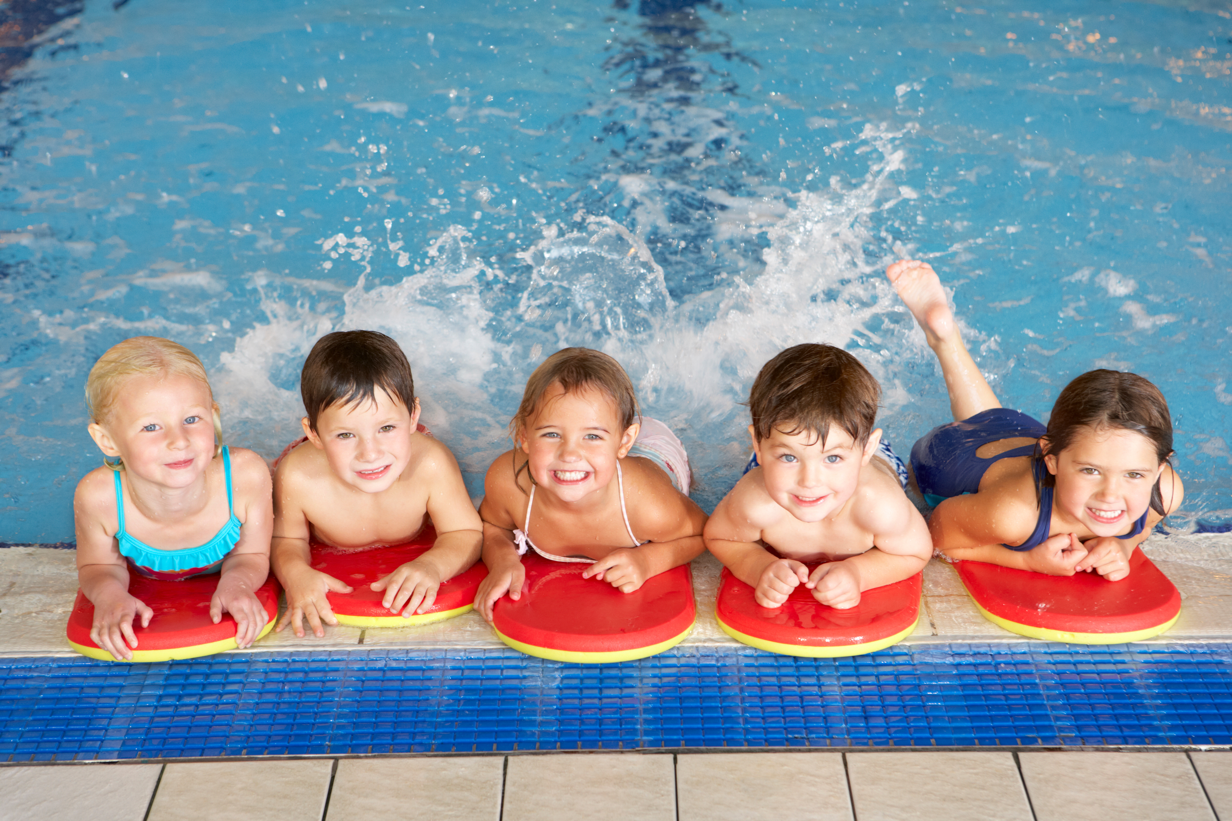 Schwimmanfänger mit Schwimmbrettern am Beckenrand